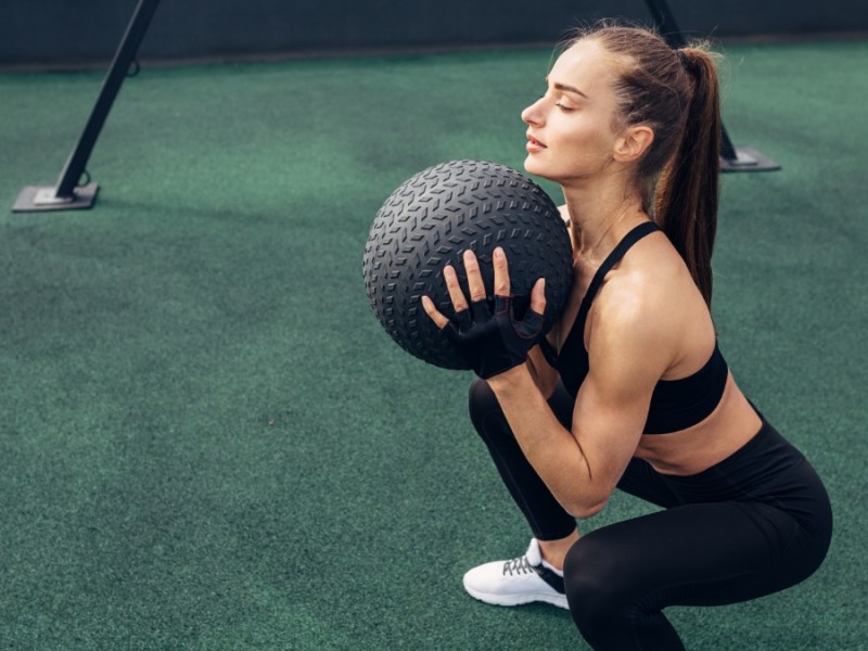 Ein Frau trainiert mit einem Medizinball.