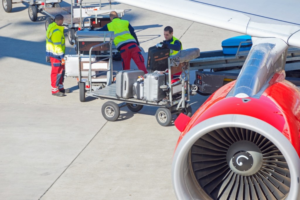 Gepäck wird von Mitarbeitern am Flughafen in ein Flugzeug verladen.