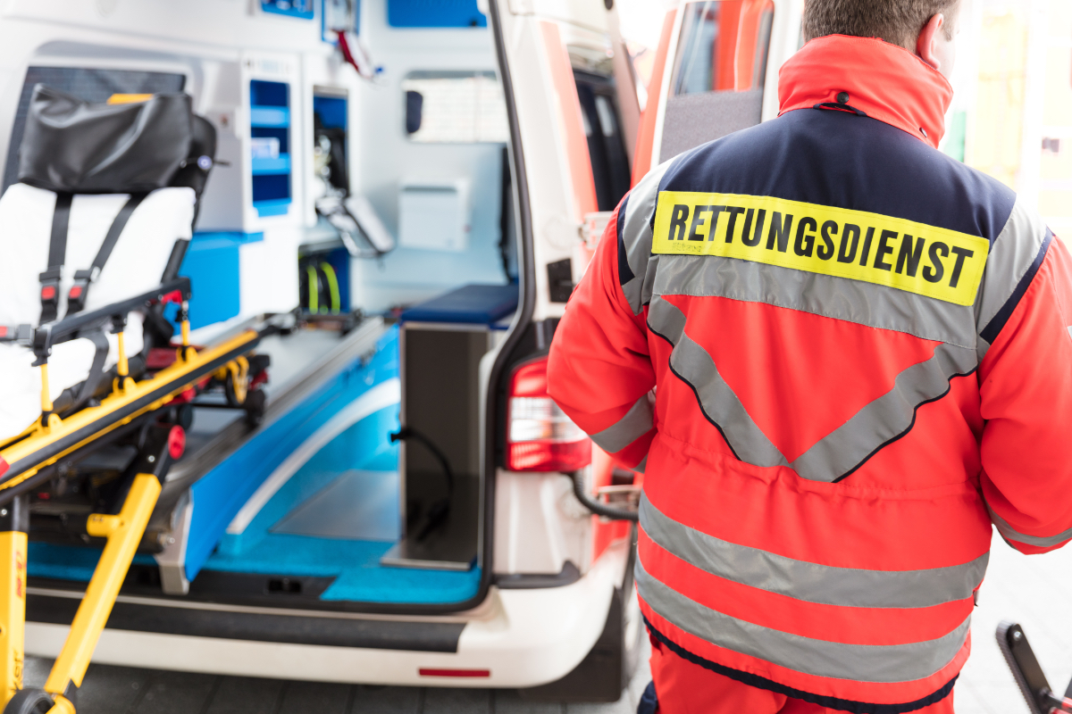 Ein Sanitäter steht vor einem offenstehenden Rettungswagen.