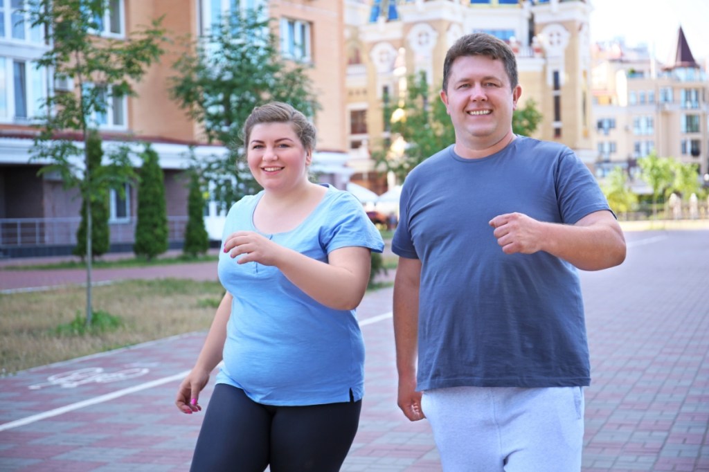 Ein Mann und eine Frau laufen auf einem Gehweg nebeneinander.