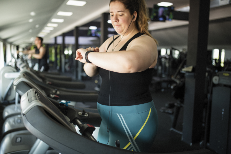 Eine Frau mit Kopfhörern läuft auf einem Laufband im Fitnessstudio