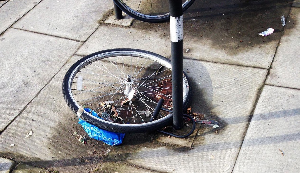 Ein Vorderreifen von einem Fahrrad, der an einem Pfeiler angeschlossen ist