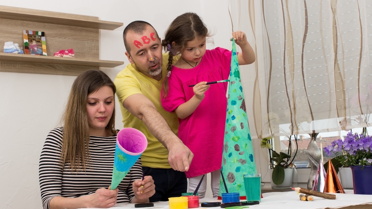 Mutter und Vater haben Spaß beim Bemalen von Schultüten