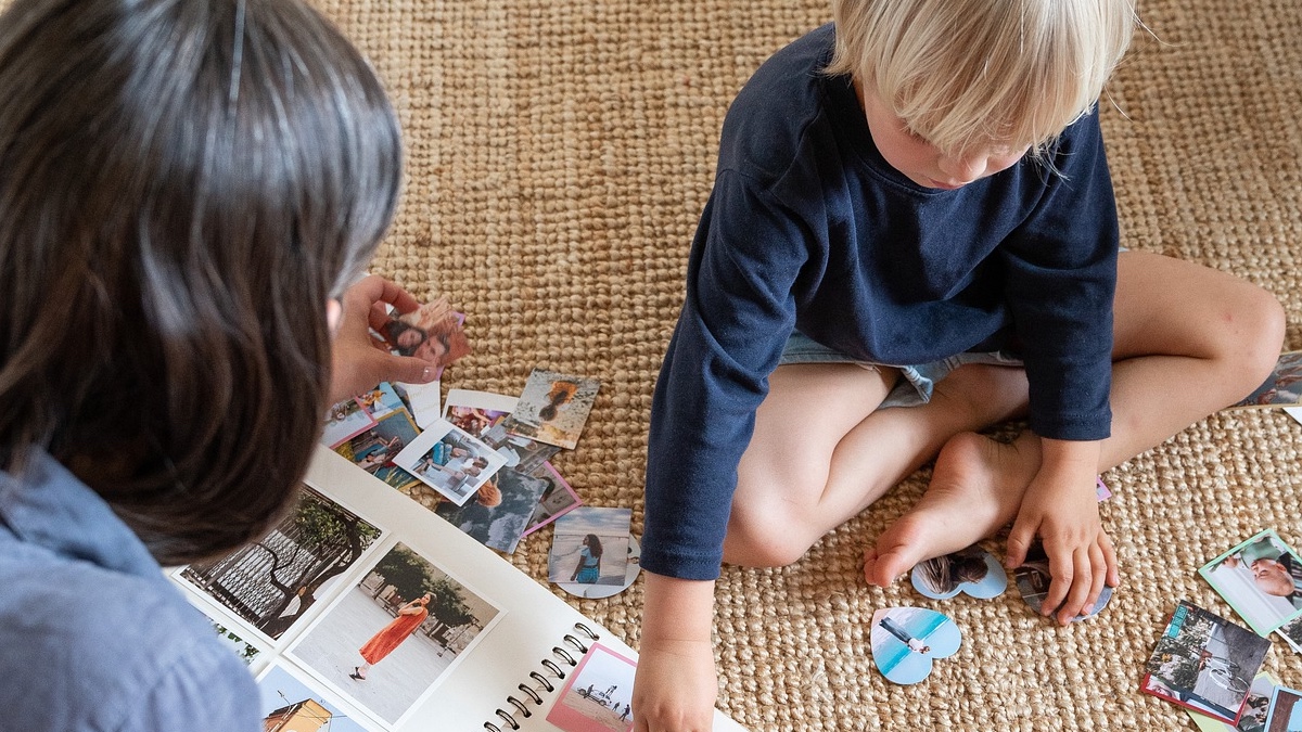 Eine Mutter bastelt mit ihrem Sohn an einem Fotoalbum.