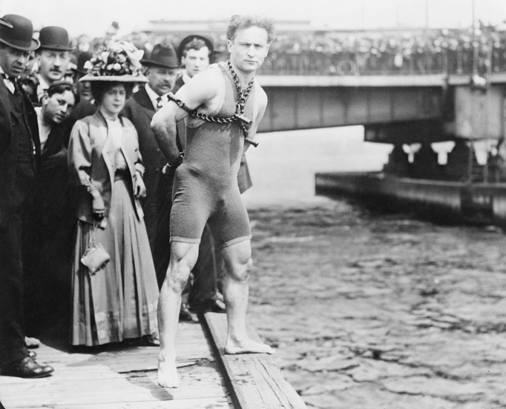 Ein Schwarzweiß-Foto vom gefesselten Harry Houdini vor seinem Sprung in den Charles River, 1904.