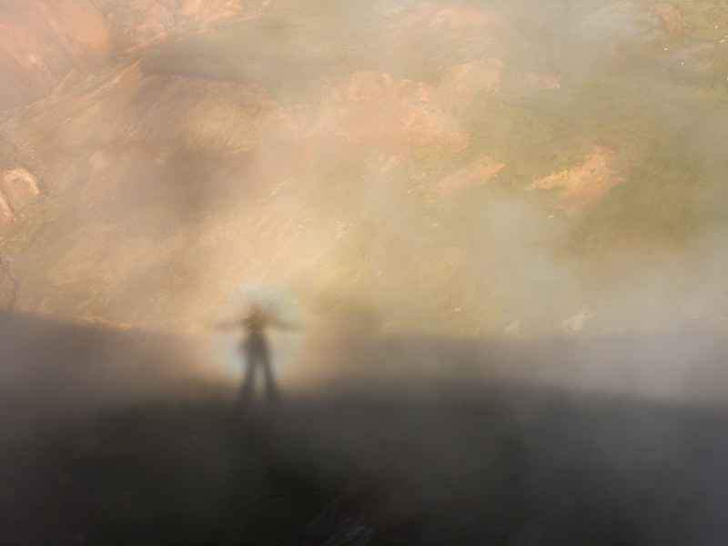 Ein Bild von einer Geistererscheinung, einem sogenannten 'Brockengespenst' im Nebel auf einem Berg.