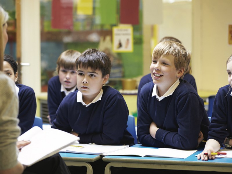 Schüler sitzen im Unterricht vor ihrer Lehrerin.