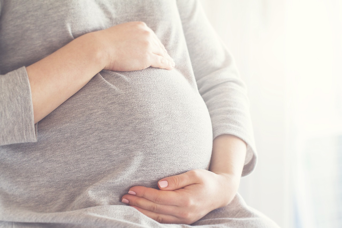 Eine schwangere Frau hält sich den Bauch.