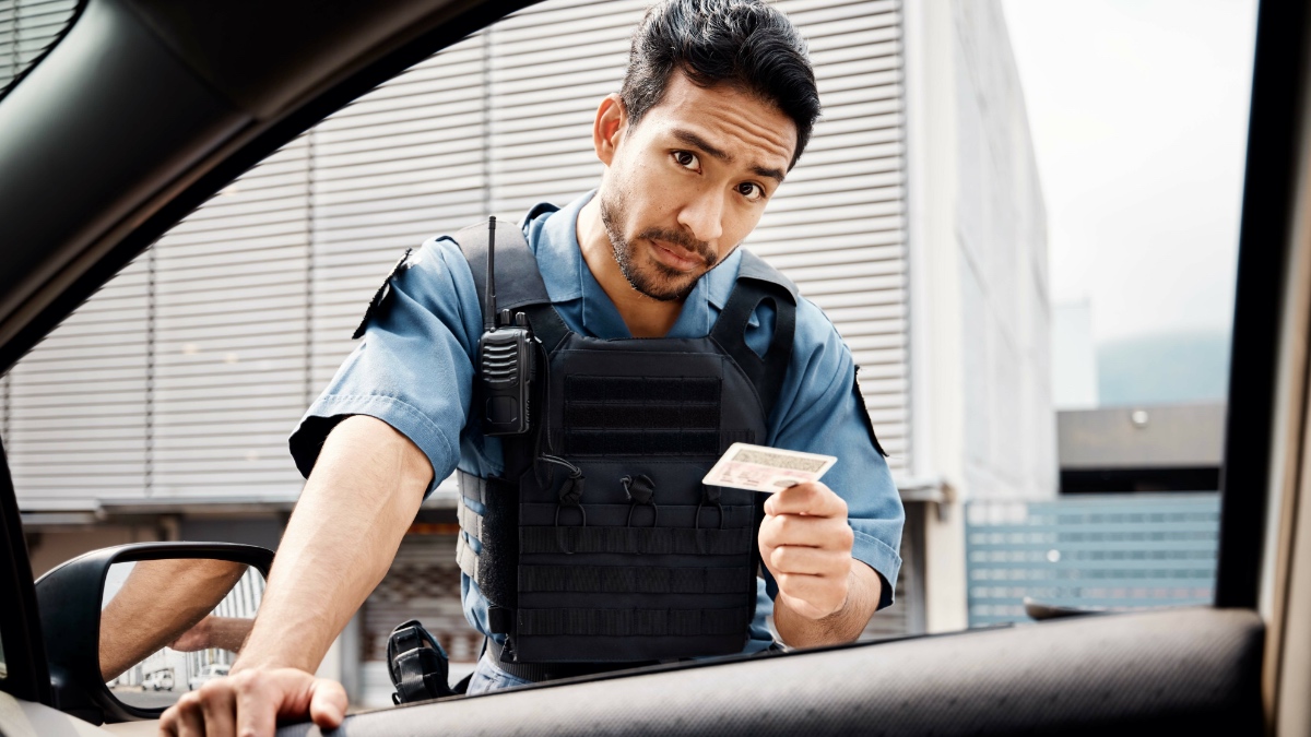 Ein Polizist kontrolliert den Ausweis eines Autofahrers.