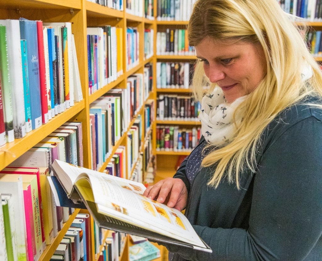 Eine Mutter in einer Bibliothek blättert in einem Buch.