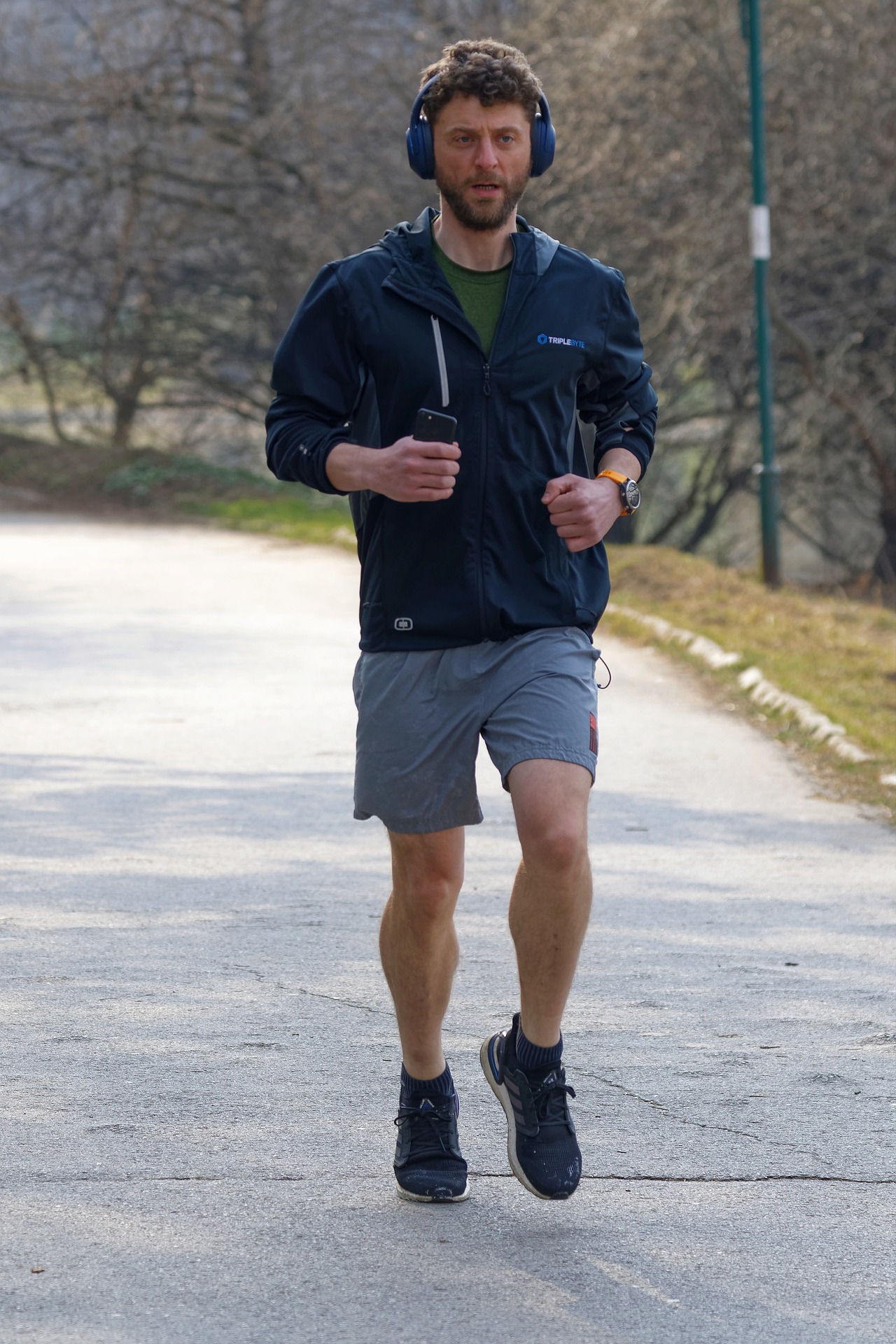 Ein Mann joggt durch einen Park und hört dabei Musik über Kopfhörer.