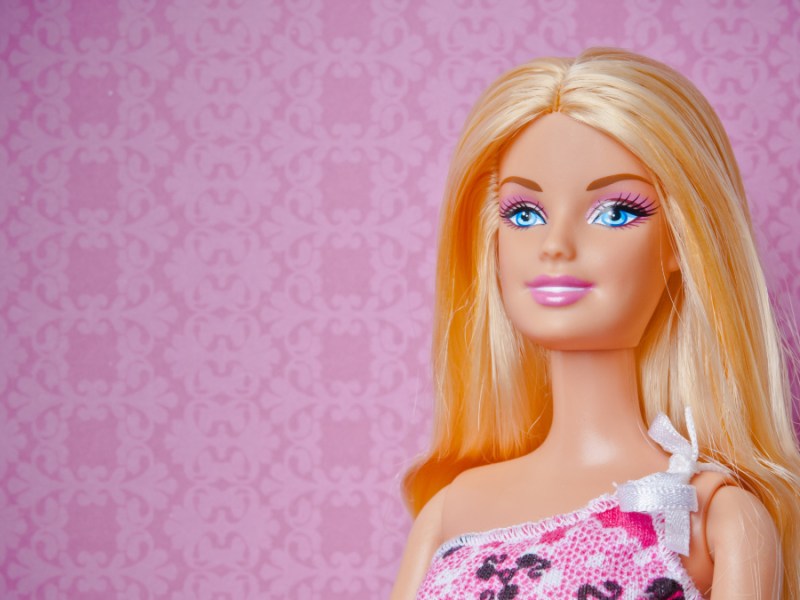 Eine blonde Barbie-Puppe vor einem pinken Hintergrund