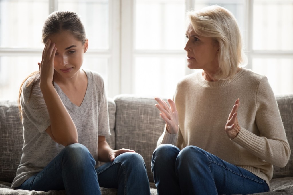 Verärgerte reife Mutter belehrt ihre erwachsene Tochter zu Hause auf der Couch sitzt.