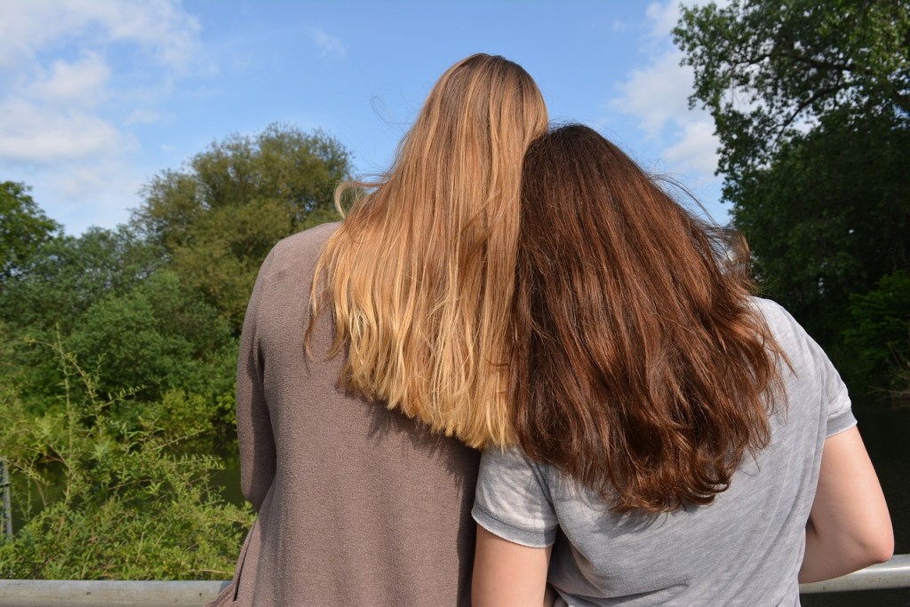 Zwei Freundinnen lehnen die Köpfe aneinander