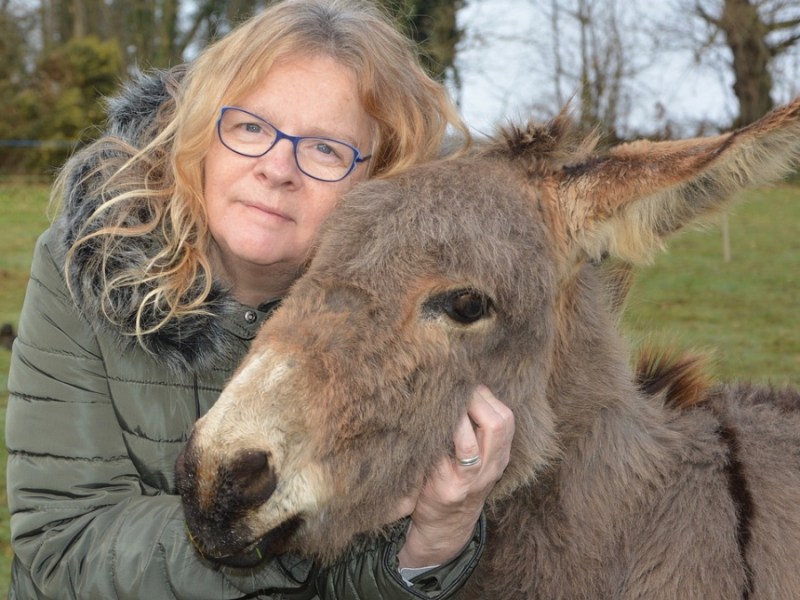 Eine Frau umarmt einen Esel auf einer Weide.