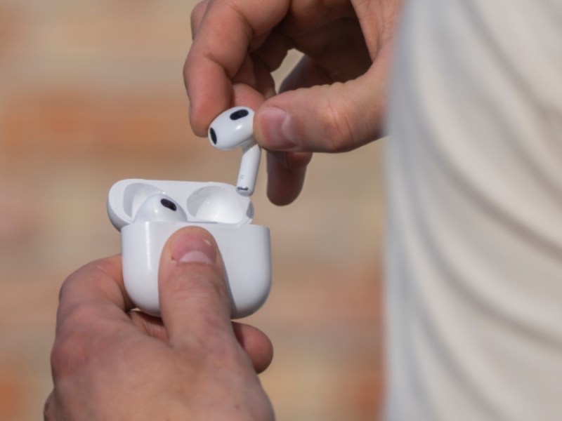 Ein Mann hält AirPods-Kopfhörer in seiner Hand.