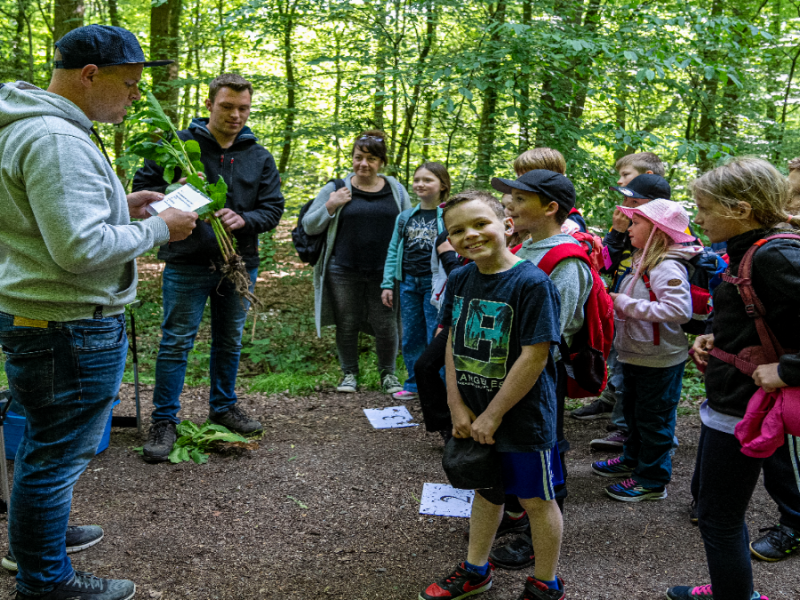 Eine Schulklasse im Wald, ein Schüler lacht in die Kamera.