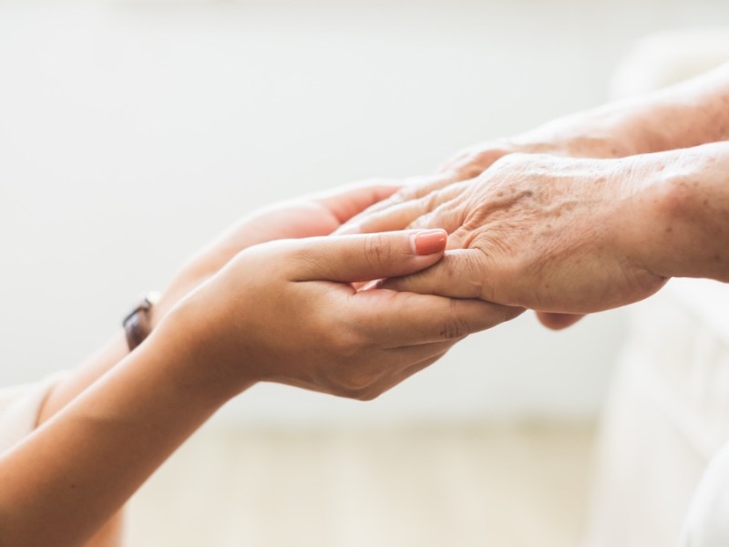 Junge Hand hält Hand von Rentner.